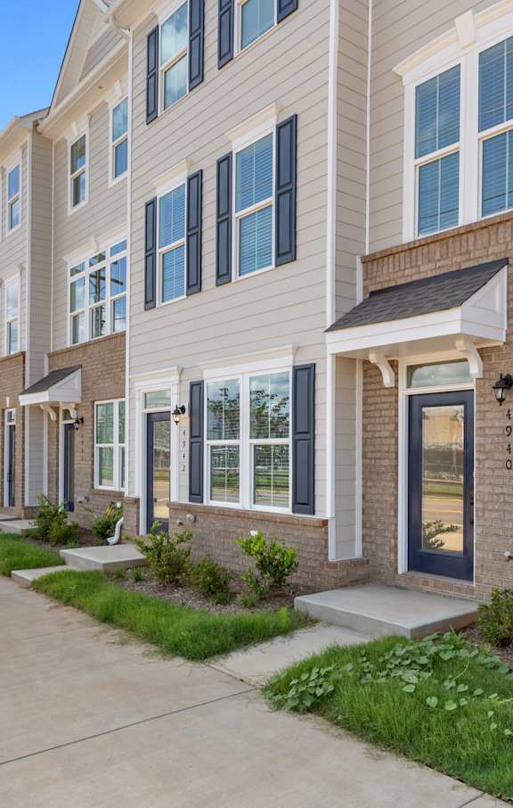 A row of modern townhouses with a tree on the left.