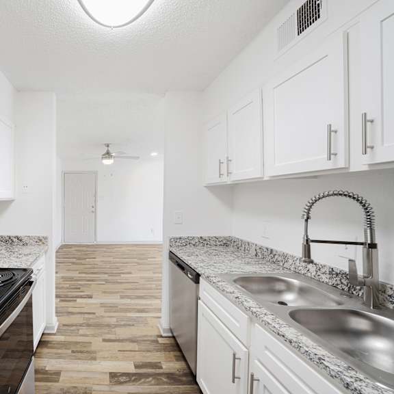 A kitchen with white cabinets and a black fridge.