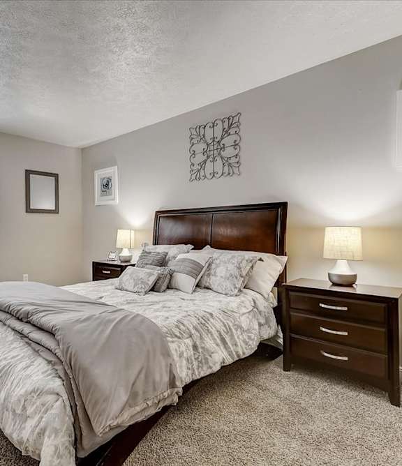 A bedroom with a large bed, nightstands, and a dresser.
