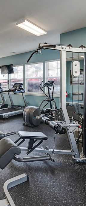 A gym with a variety of equipment including treadmills, weights, and exercise machines.
