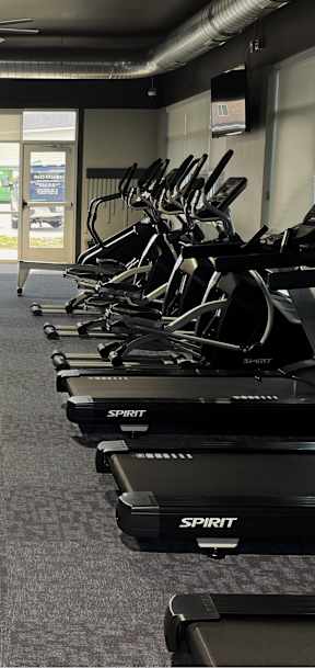 A gym with treadmills and elliptical machines.