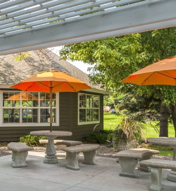 a group of benches with umbrellas on a patio  at Mallard Ridge, Maple Grove, 55369