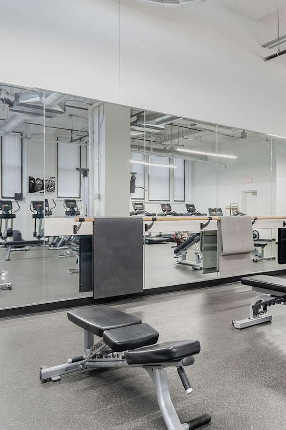 A gym with a variety of equipment including weights and benches.