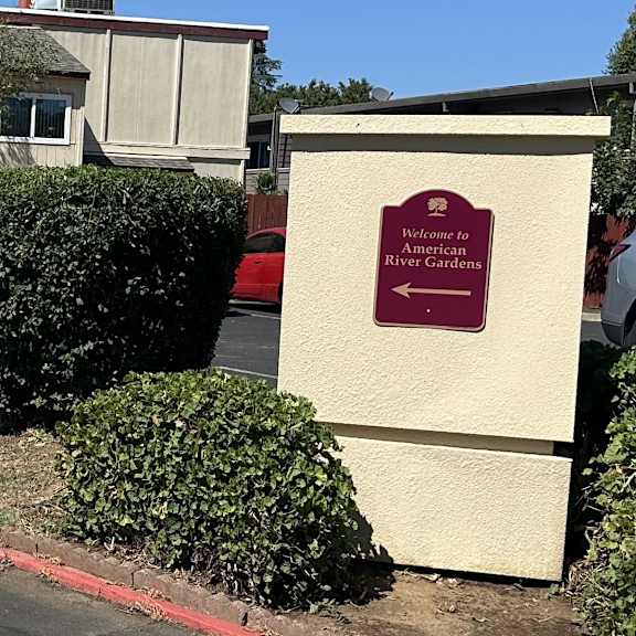 A sign for the Waterside American River Gardens is on a wall.