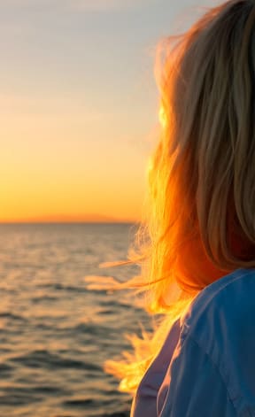 two women watching the sunset over the ocean
