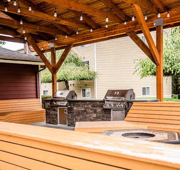 A wooden picnic table under a wooden pergola at Ellyson Apartment Homes in Tacoma, WA