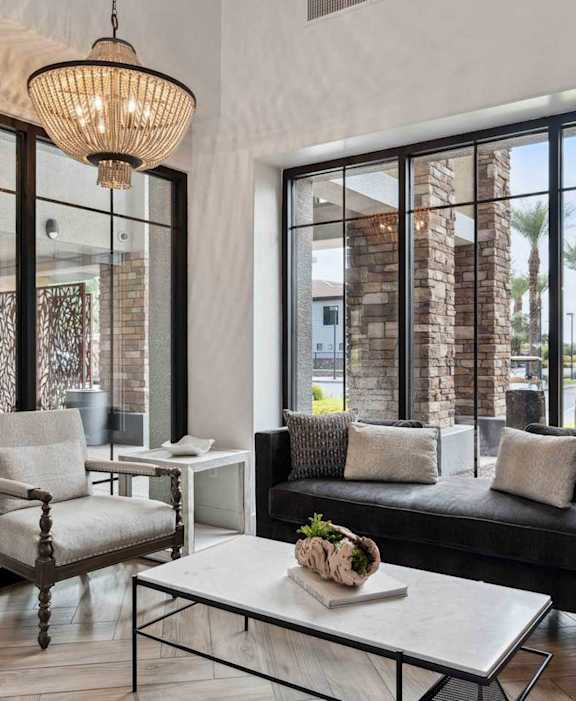 A modern living room with a black couch, a white coffee table, and a large window.