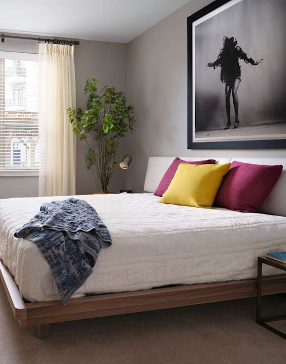 A bedroom with a large bed and a painting on the wall.