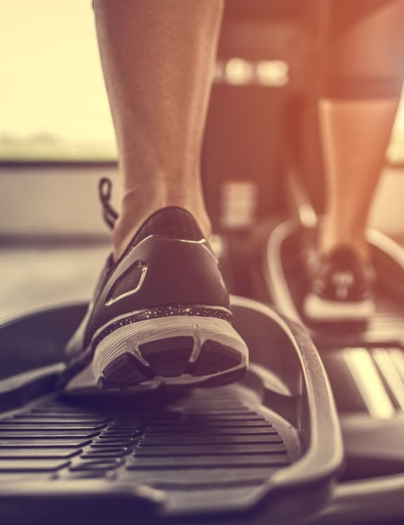 Close Up of Man's Shoes While He Uses Elliptical Machine in Fitness Center