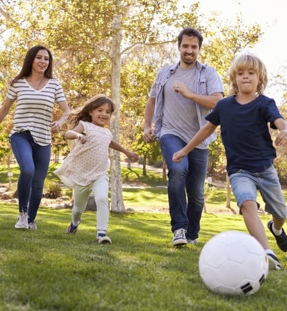 Mother and Father Playing Soccer in Field with Son and Daughter