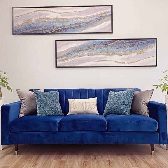 a living room with a blue couch and two paintings on the wall