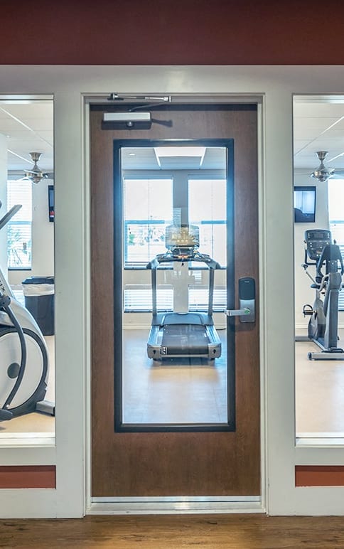 The fitness center with cardio and other exercise equipment a green and red playground with stairs and a slide at Villas on the Strand apartments in Galveston, TX
