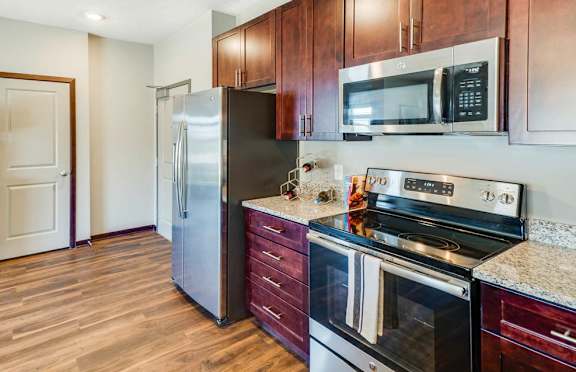 A kitchen with wooden cabinets and a stainless steel refrigerator.