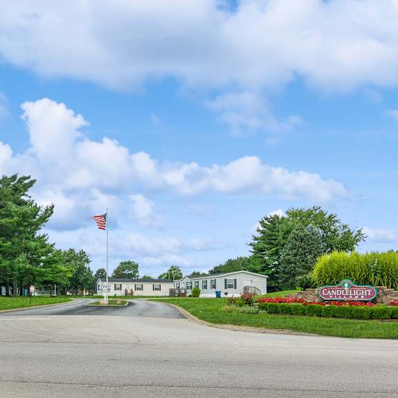 A road with a flag on a pole and a sign that says "Candlelight Village".