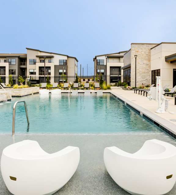 Two white chairs are placed in the middle of a pool.