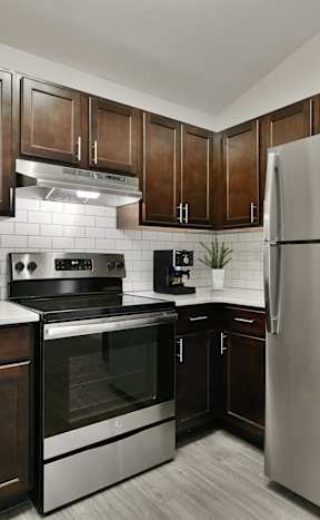 A kitchen with dark wood cabinets and stainless steel appliances.