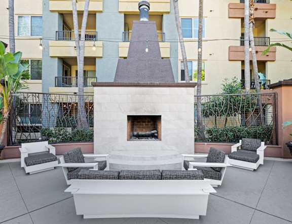 A patio with a table and chairs is surrounded by a grassy area and apartment buildings at The Kitt at Warner Center in Woodland Hills, California, 91303