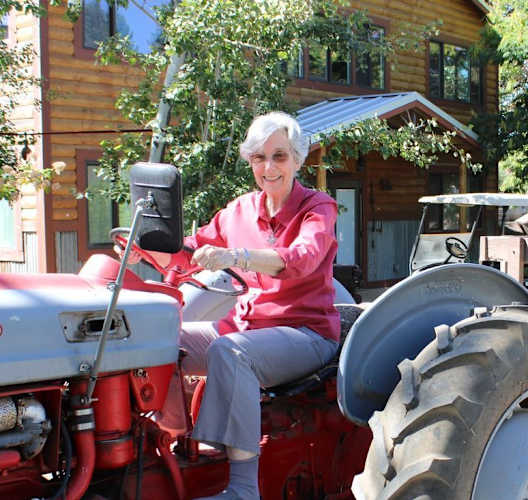 a woman sitting on a red tractor with a load of hay at Campus Commons Senior Living, Sacramento, CA 95825