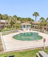 A pool surrounded by a fence and benches in front of apartment buildings.
