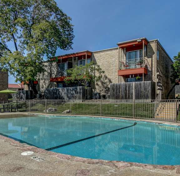 A swimming pool surrounded by a fence and buildings.