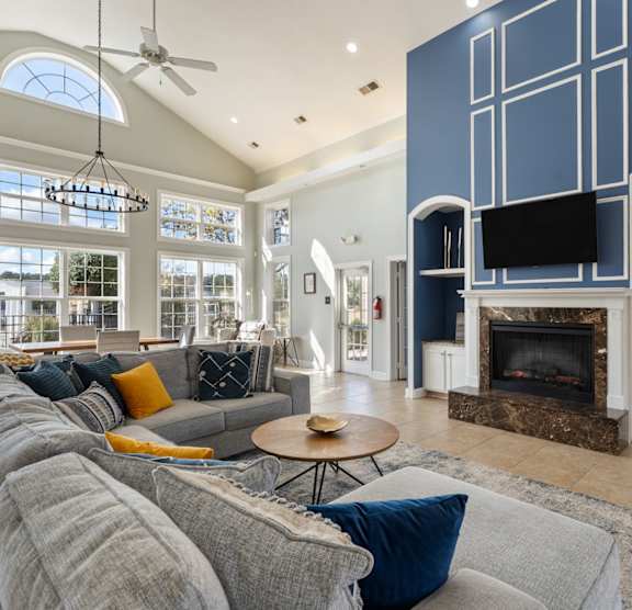 A living room with a grey couch and a fireplace. at Village on the Lake Apartments, Spring Lake, NC, 28390