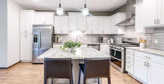 A modern kitchen with a table and chairs in the middle.