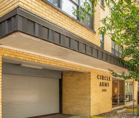 a building with a garage door and trees in front of it