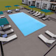 A pool with loungers and umbrellas is surrounded by a building.