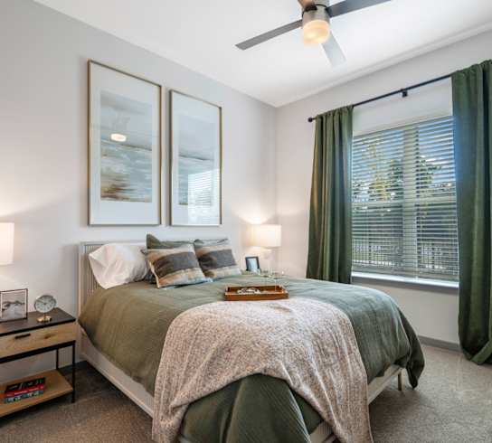 A bedroom with a bed, nightstand, and window.