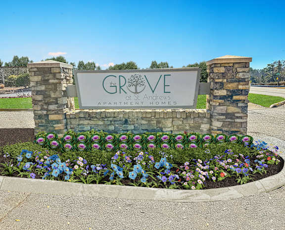 A sign for Grove at Andrews Apartment Homes is surrounded by flowers.
