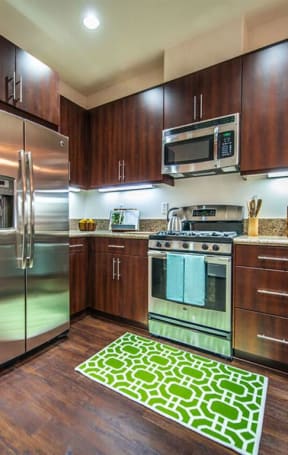 a kitchen with stainless steel appliances and wooden cabinets at The Vines at Riverpark, LLC, Oxnard California