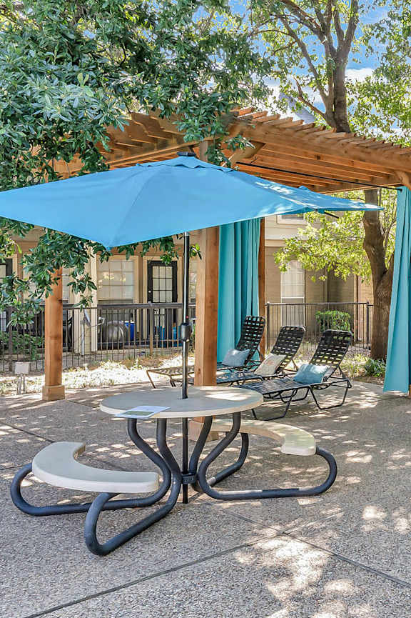 A patio with a table and chairs under a blue umbrella.