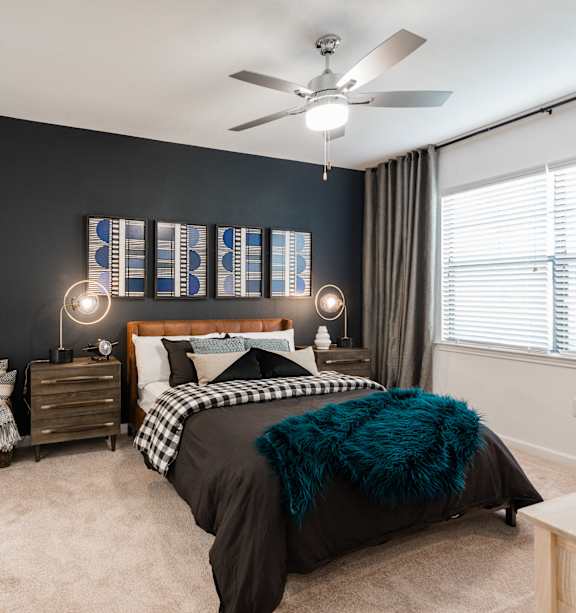 A bedroom with a bed, nightstands, and a ceiling fan.