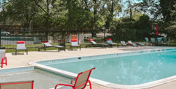 a swimming pool with red chairs around it