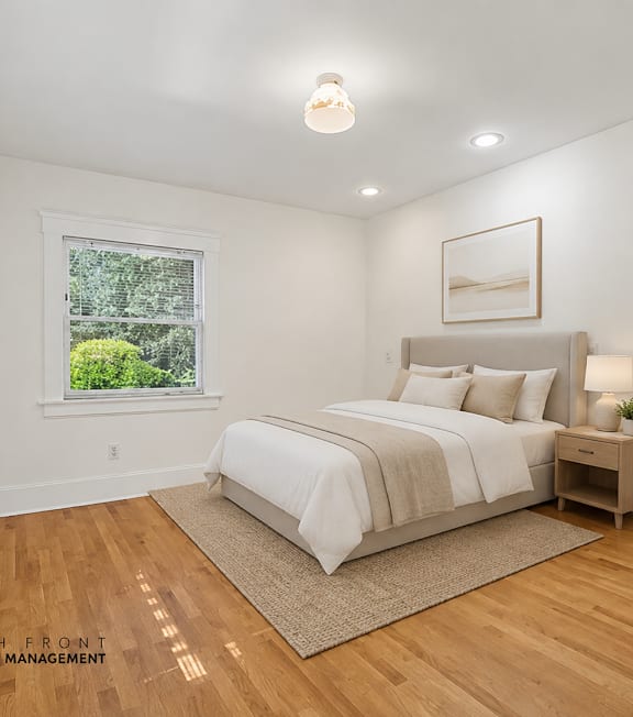 A well-lit bedroom with a large bed and a painting on the wall.