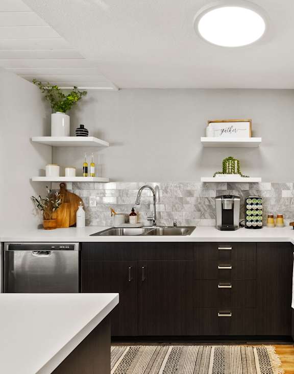 A modern kitchen with a white countertop and black cabinets.