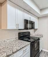 A kitchen with a black stove top oven and white cabinets.