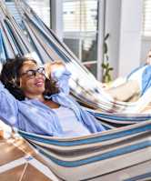 A woman in a blue shirt is relaxing in a hammock.