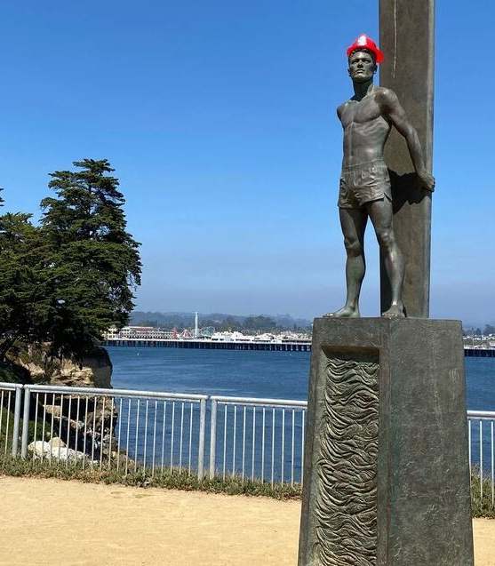 A statue of a man stands on a pedestal by a body of water. at Westmont Place Townhomes Apartments, Santa Cruz, California