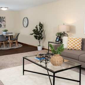 A living room with a grey couch, a coffee table, and a dining table with chairs.
