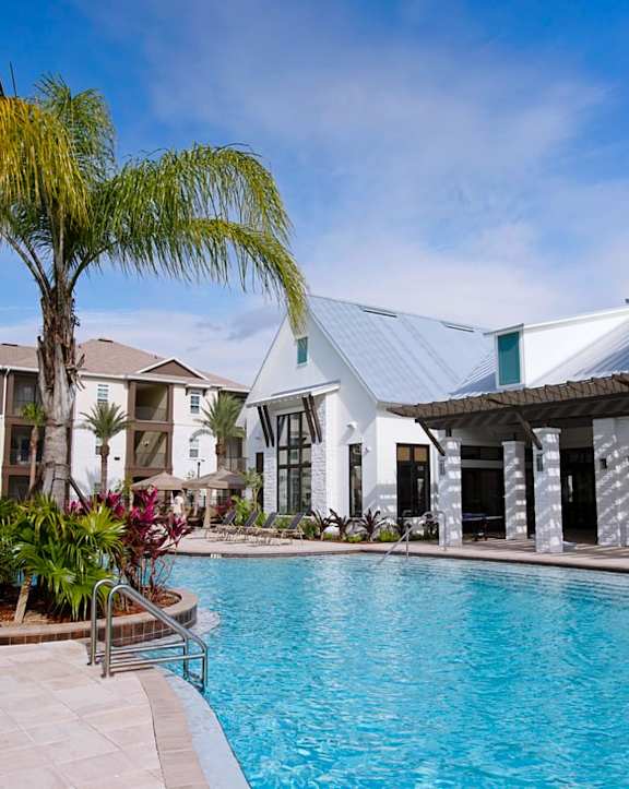 a bar with a grill next to a swimming pool with a building in the background at Cabana Club Apartments in Jacksonville, Florida 32256