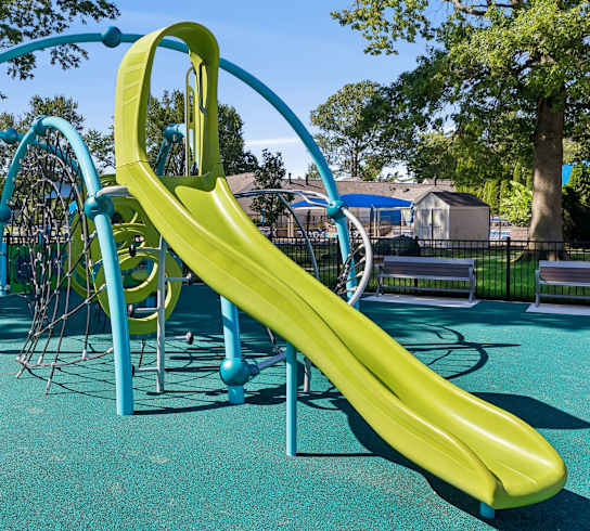 A playground with a yellow slide and a blue slide.