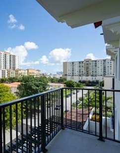 A balcony overlooks a cityscape with buildings and trees.
