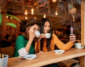 two woman drinking coffee at a cafe and taking a selfie