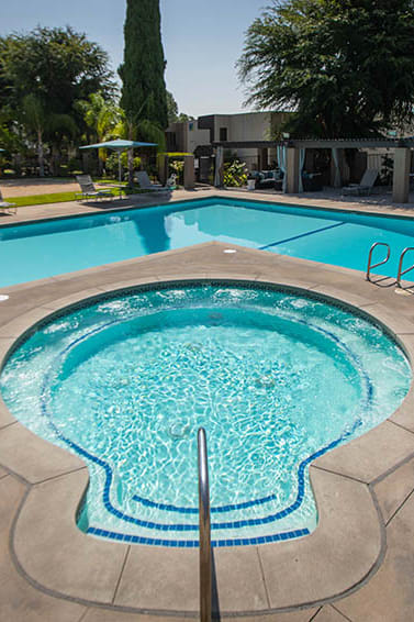 a swimming pool with a chair and table next to it at Aspire Upland Apartments, Upland, 91786