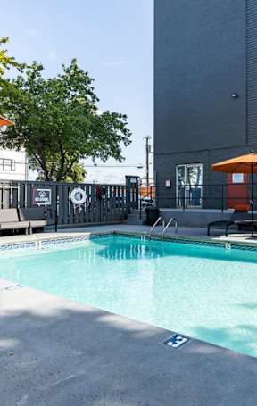A pool with a blue tinted water and orange umbrellas.