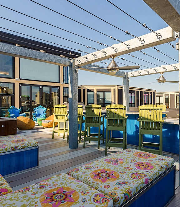 a deck with a pergola and a dining area with blue and yellow chairs
