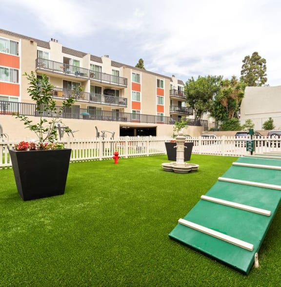 a large yard with a green shuffleboard court and an apartment building