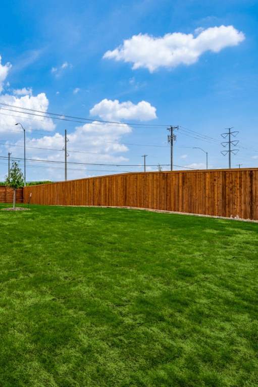 A backyard with a wooden fence and a green lawn.