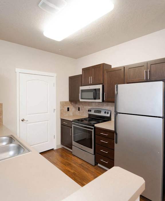 A kitchen with a refrigerator, oven, sink, and microwave.